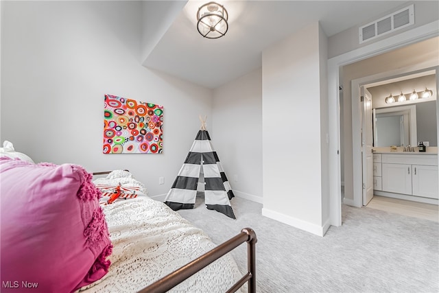 carpeted bedroom featuring ensuite bathroom and sink