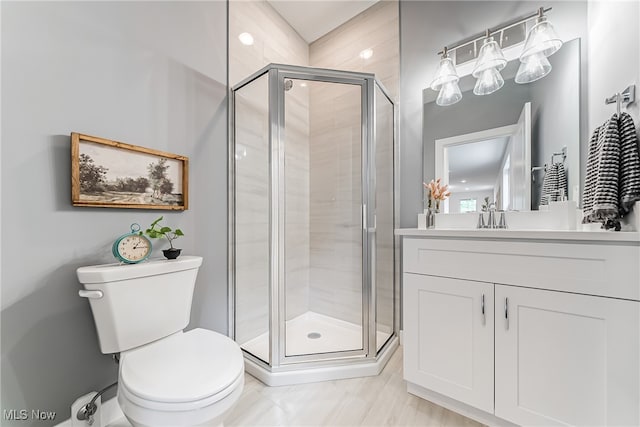 bathroom with a shower with shower door, vanity, and toilet