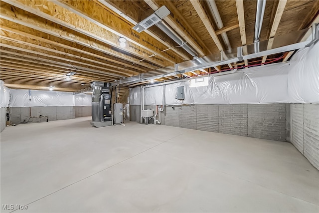 basement featuring water heater, heating unit, brick wall, electric panel, and sink