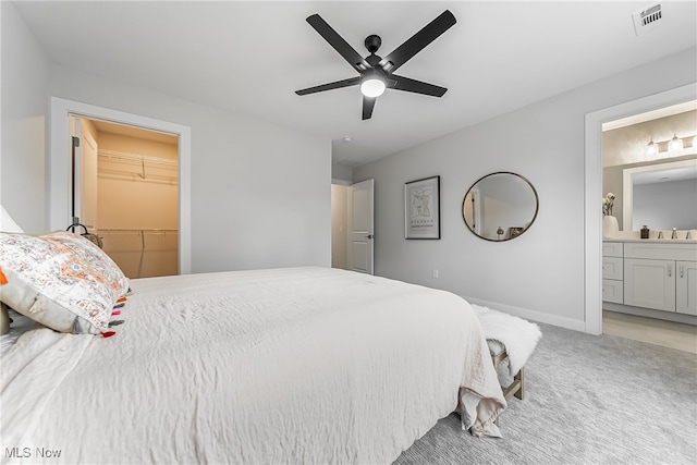 bedroom featuring a closet, ceiling fan, a walk in closet, carpet, and ensuite bath