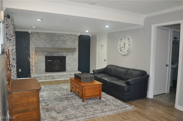 living room with a textured ceiling, a fireplace, ornamental molding, and hardwood / wood-style floors