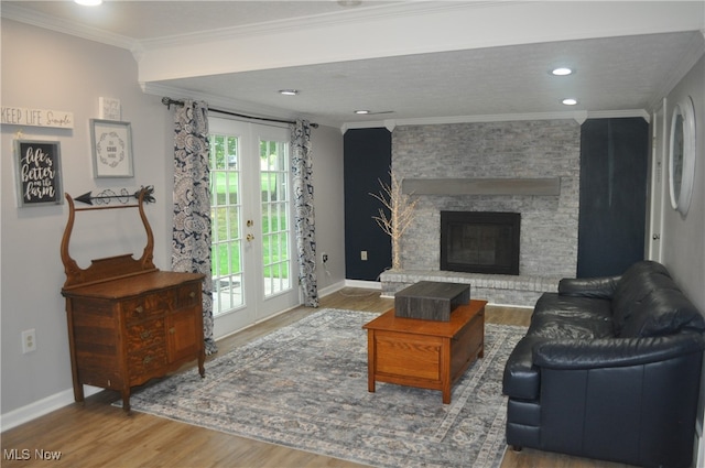 living room with a stone fireplace, french doors, hardwood / wood-style floors, and crown molding