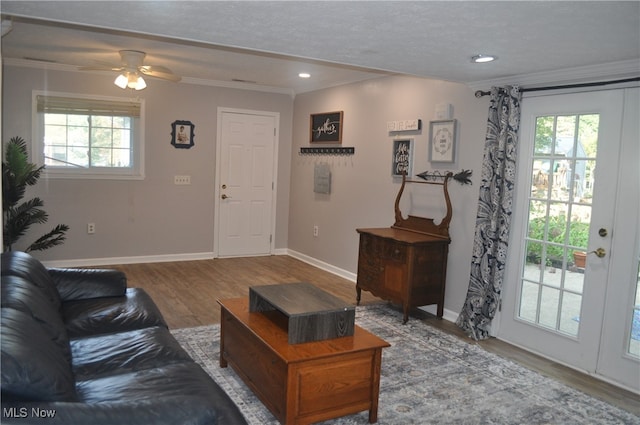 living room with a healthy amount of sunlight, crown molding, ceiling fan, and wood-type flooring