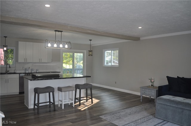 kitchen with beamed ceiling, hanging light fixtures, dark wood-type flooring, white cabinetry, and a center island