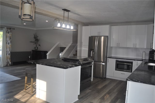 kitchen featuring appliances with stainless steel finishes, white cabinetry, dark hardwood / wood-style floors, and pendant lighting