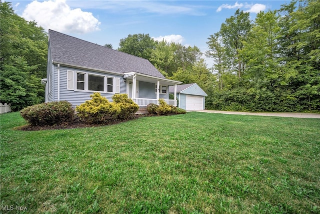 view of front of house with an outbuilding, covered porch, a front yard, and a garage