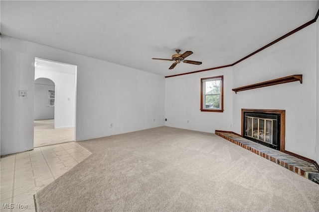 unfurnished living room featuring ceiling fan, ornamental molding, light tile patterned floors, and a brick fireplace