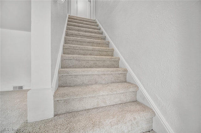 staircase featuring carpet flooring