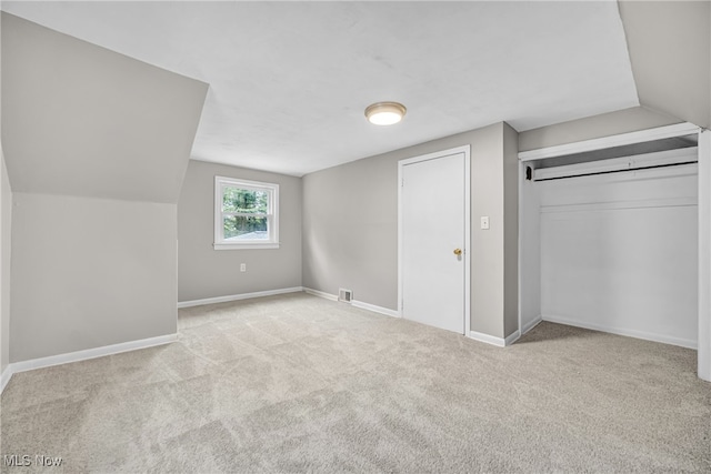 additional living space with light colored carpet and vaulted ceiling