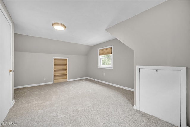 bonus room featuring vaulted ceiling and light colored carpet