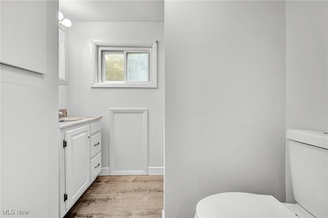 bathroom featuring vanity, wood-type flooring, and toilet