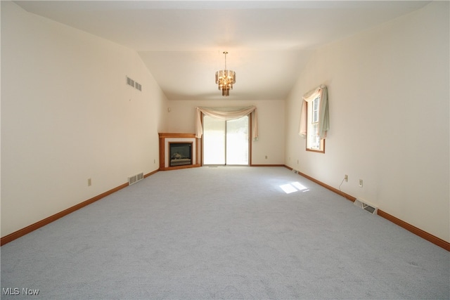 carpeted empty room featuring lofted ceiling and a chandelier