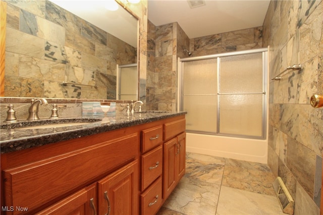 bathroom featuring dual bowl vanity, tile patterned floors, and bath / shower combo with glass door