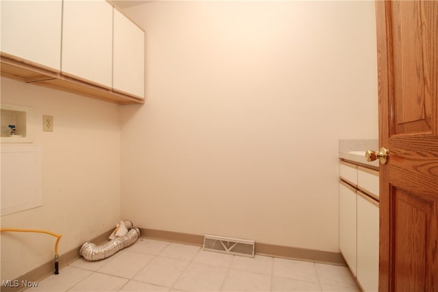 clothes washing area with light tile patterned floors, cabinets, and hookup for a washing machine