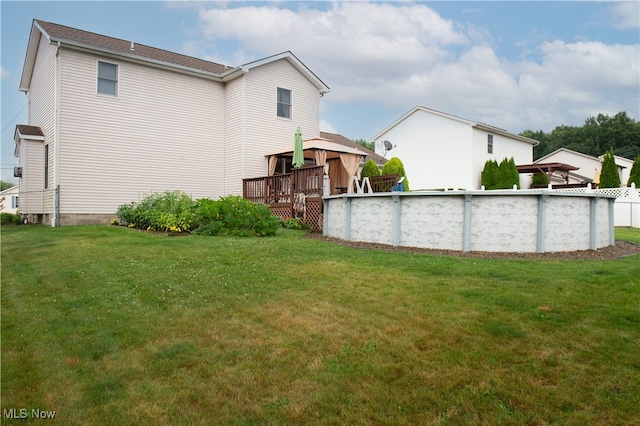 back of house featuring a lawn and a pool side deck