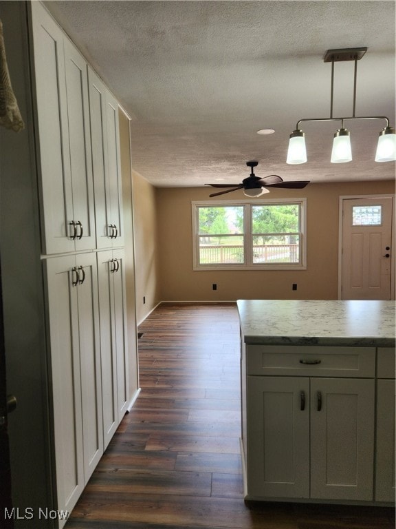 kitchen featuring dark hardwood / wood-style flooring, a textured ceiling, ceiling fan, white cabinets, and decorative light fixtures