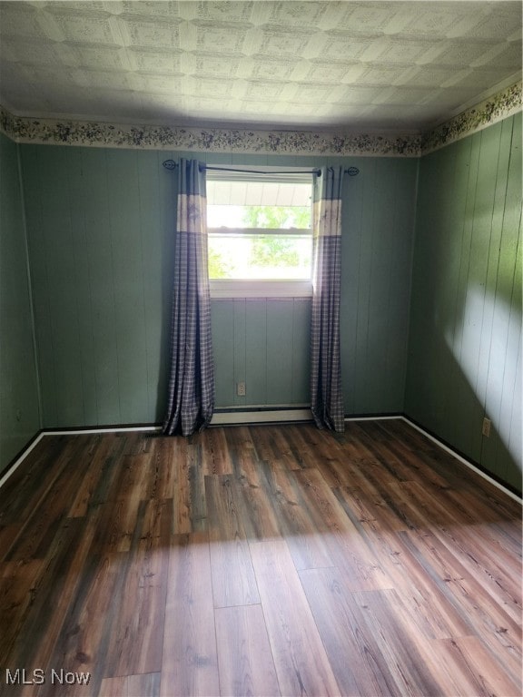 empty room with wood-type flooring and a baseboard radiator