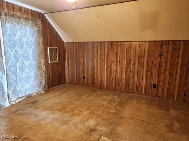 additional living space featuring wood walls, vaulted ceiling, and carpet floors