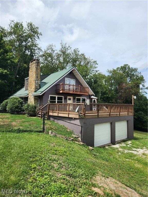 view of front of house featuring a garage, a front lawn, and a wooden deck