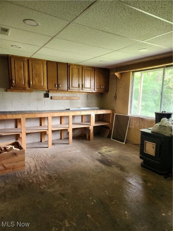 misc room featuring a wood stove and a paneled ceiling