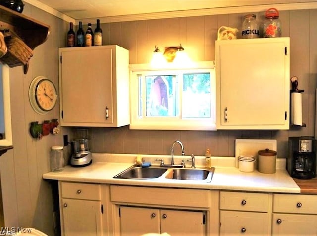 kitchen featuring tasteful backsplash, sink, ornamental molding, and white cabinets