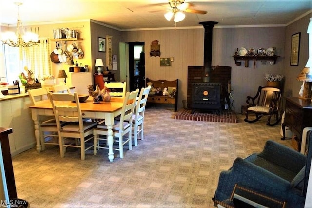 carpeted dining space featuring a wood stove, crown molding, and ceiling fan with notable chandelier