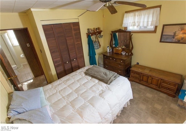 carpeted bedroom with ceiling fan and a closet