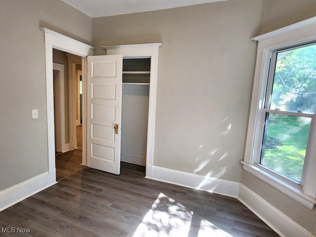 unfurnished bedroom featuring dark hardwood / wood-style flooring and a closet