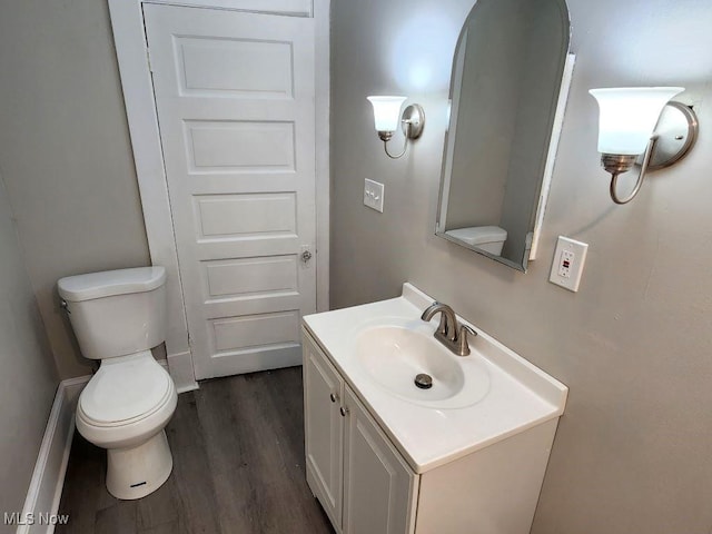 half bathroom featuring vanity, toilet, and wood finished floors