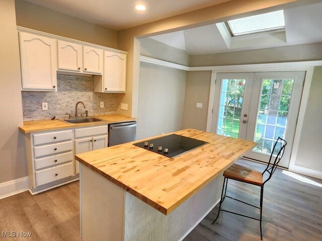 kitchen featuring stainless steel dishwasher, sink, wood-type flooring, and wood counters