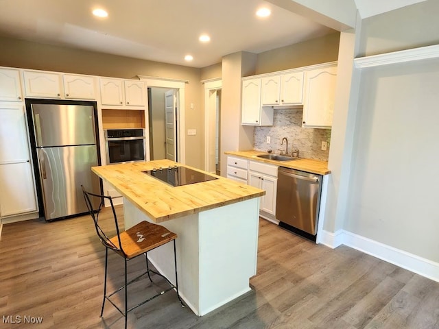 kitchen with decorative backsplash, butcher block countertops, stainless steel appliances, a kitchen island, and wood-type flooring