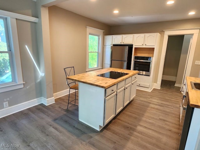 kitchen featuring stainless steel appliances, dark hardwood / wood-style flooring, white cabinets, a kitchen island, and butcher block countertops