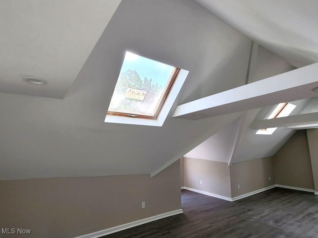 bonus room with vaulted ceiling with skylight, dark wood-style flooring, and baseboards