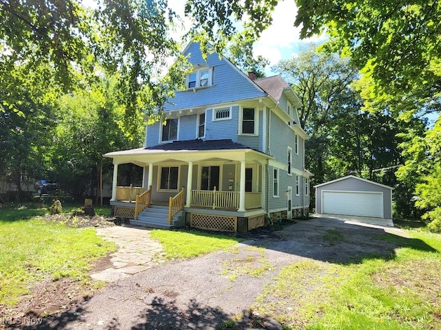 view of front of house featuring a front lawn, covered porch, a garage, and an outdoor structure