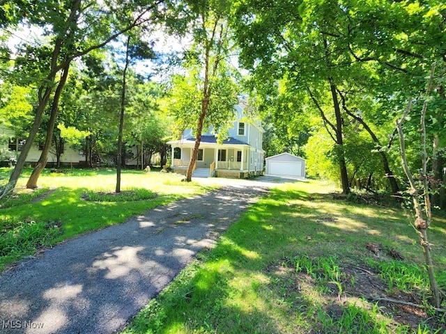 view of front facade with a garage, covered porch, a front yard, and an outdoor structure