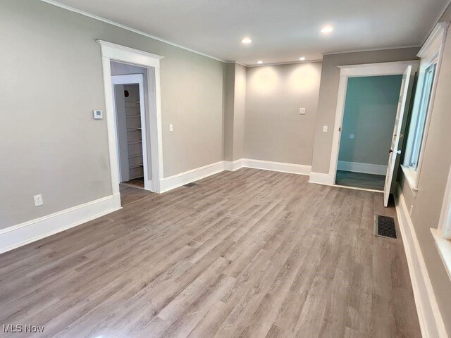 unfurnished room with light wood-type flooring and ornamental molding