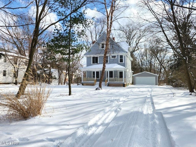 view of front facade with covered porch, a detached garage, a chimney, and an outbuilding