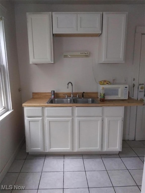 kitchen featuring light tile patterned flooring, sink, and white cabinets