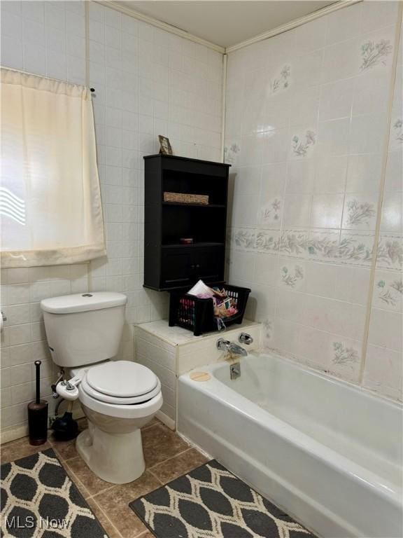 bathroom featuring tile patterned flooring, tile walls, a washtub, and toilet