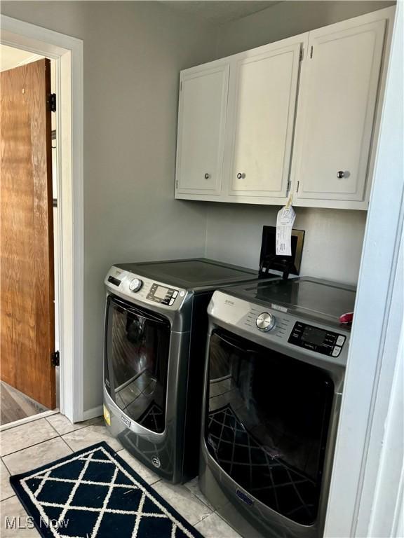 laundry area featuring light tile patterned flooring, cabinets, and washer and clothes dryer