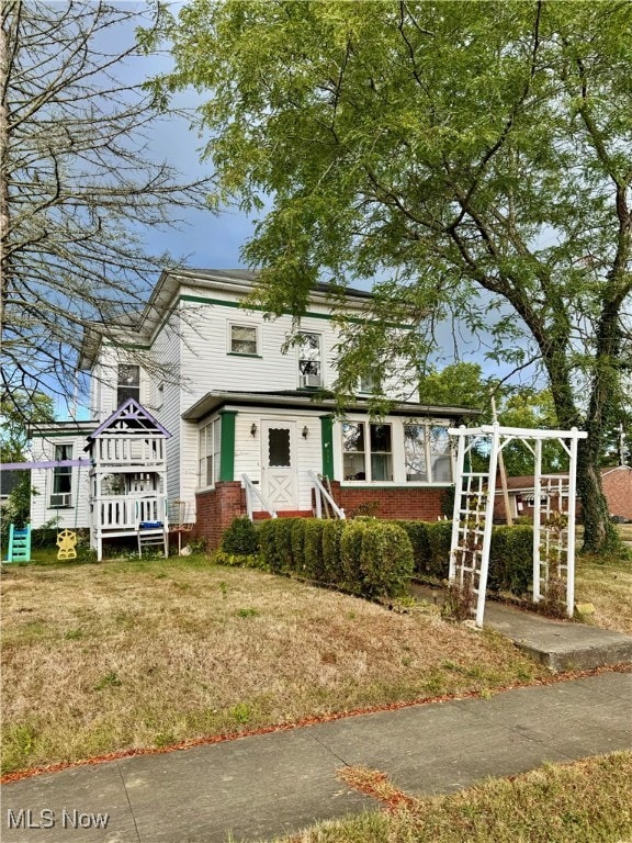 view of front of home with a playground and a front lawn