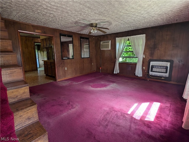 unfurnished living room featuring ceiling fan, heating unit, hardwood / wood-style flooring, and a wall mounted air conditioner