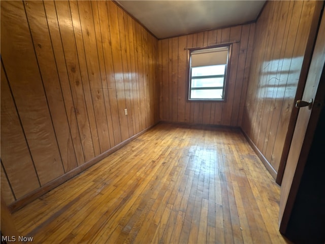 empty room featuring wooden walls and hardwood / wood-style flooring