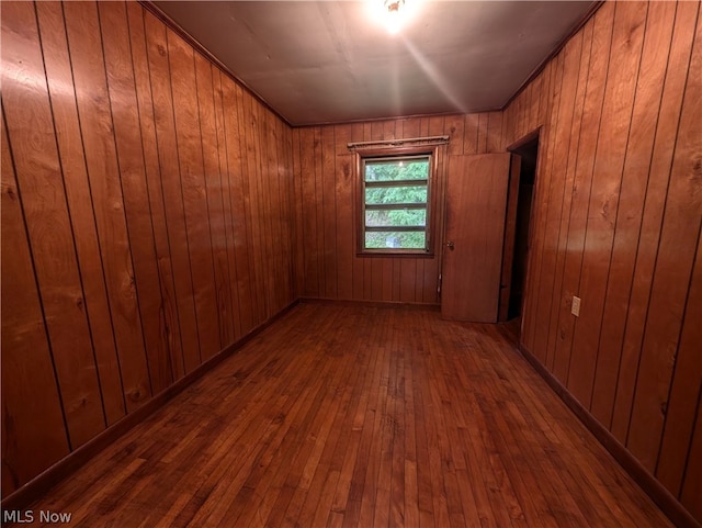 unfurnished room with dark hardwood / wood-style flooring and wooden walls