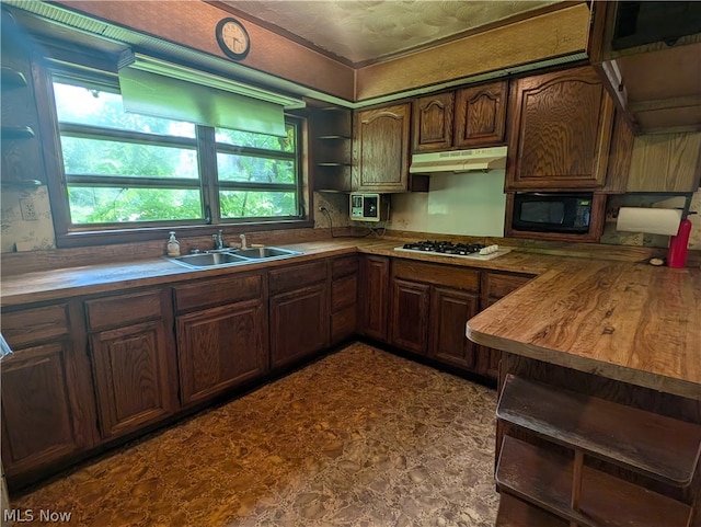 kitchen with stainless steel gas stovetop, dark brown cabinetry, wooden counters, black microwave, and sink