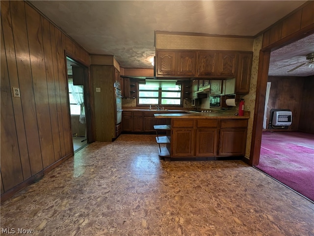 kitchen featuring wooden walls, ceiling fan, double oven, kitchen peninsula, and built in microwave