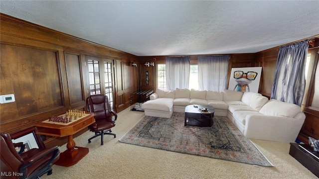 living room with light carpet, wood walls, and a textured ceiling