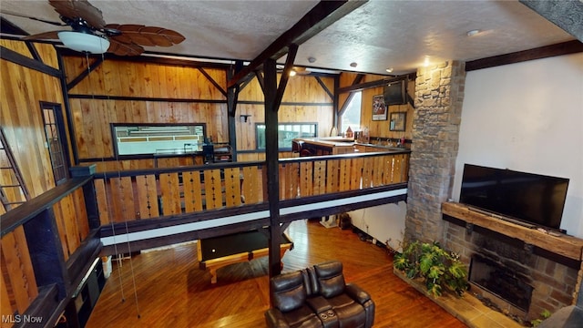 workout room featuring ceiling fan, wood walls, hardwood / wood-style floors, and a textured ceiling