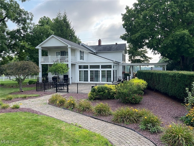 back of house featuring a balcony and a lawn