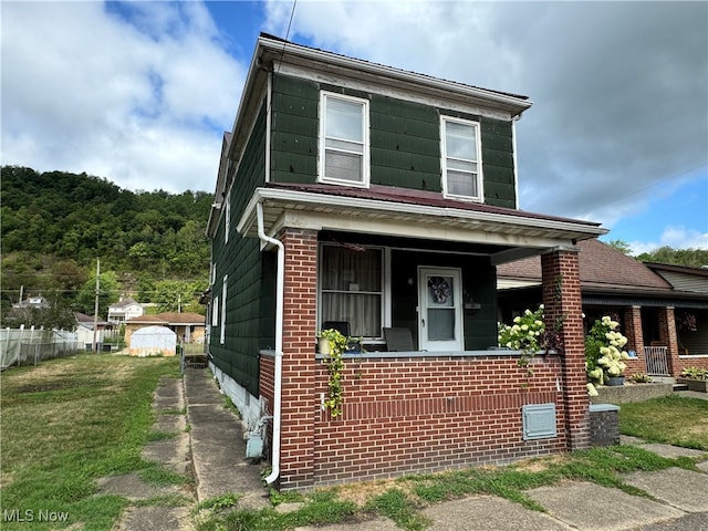 view of front facade featuring central AC, covered porch, and a front yard